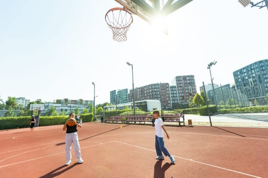 Concept of sports, hobbies and healthy lifestyle. Young people playing basketball on playground outdoors. High quality photo