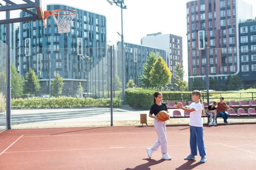 Teenager girl street basketball player with ball on outdoor city basketball court. High quality photo