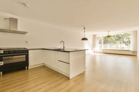 a kitchen with wood floors and an oven in the center of the photo is taken from the living room to the dining area