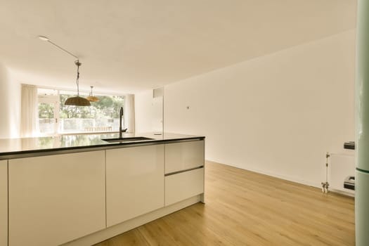 a kitchen with white cabinets and black counter tops on the island in front of the sink is open to the living room