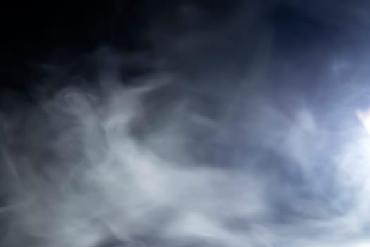 Abstract design of white cloud on a dark background. Blurry motion of smoke.