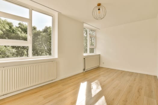 an empty room with wood flooring and large windows looking out to the trees outside in the room is very clean