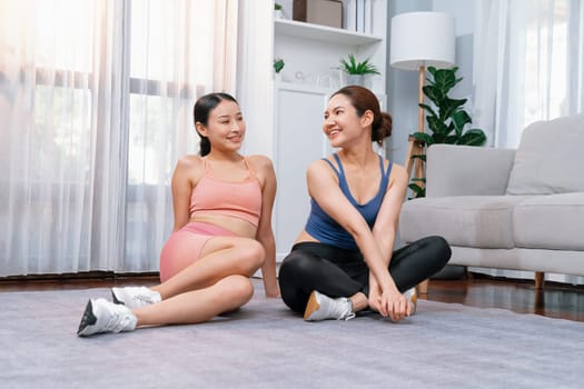 Asian woman in sportswear with her trainer or workout buddy, smiling and posing cheerful gesture. Home workout training or exercise fitness lifestyle in pursuit of healthy lifestyle. Vigorous