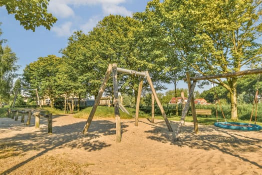 a playground area with swings, slides and slides in the sand at an outdoor play area surrounded by trees