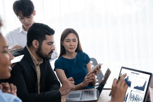 Multiracial analyst team use BI Fintech software to analyze financial data on meeting table. Financial dashboard data display on laptop screen with analyzed chart for marketing indication. Concord