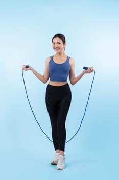 Young energetic asian woman in sportswear with jumping or skipping robe posing portrait in studio shot on isolated background. Cardio exercise tool and healthy body care lifestyle. Vigorous