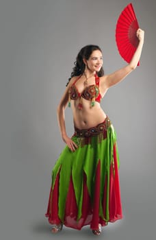 Woman in color traditional arabian costume belly dance with fan