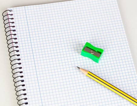 Sharp pencil and sharpener on a spiral notebook in blank