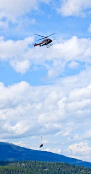 Rescue helicopter rescuing person by airlifting dangling on rope in Alberta Canada