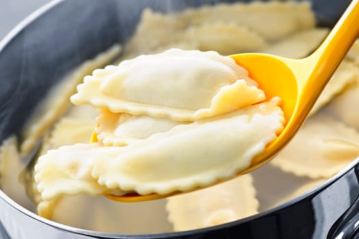 Cooked ravioli lifted from pot on spoon