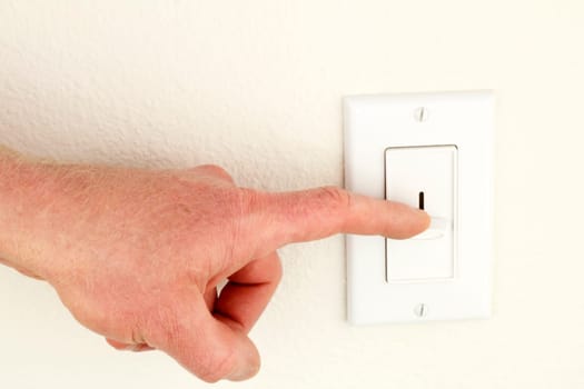Hand of a man seen pressing down a sliding overhead lighting control on a wall