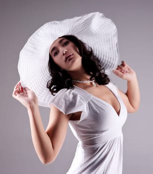 beautiful fashion model in white dress and hat on gray