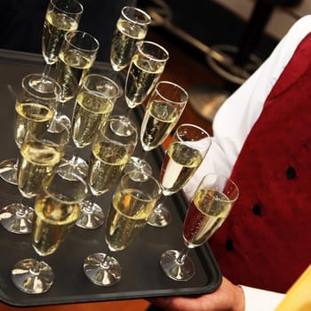 Waiter serves sparkling wine or champagne on a tray
