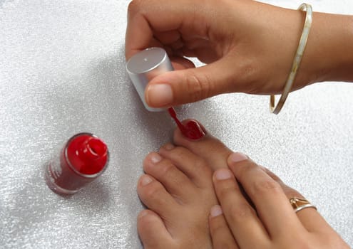 A young woman renews the nail polish on her toes,applying the new nail polish,Germany,Europe