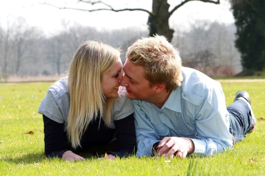 couple in love in a meadow - nose to nose - both located on the belly and laugh