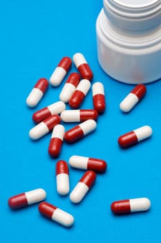white container spilling pills over blue background
