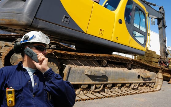 engineer, driver, with large bulldozer, digger in background