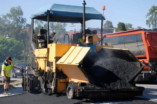 large asphalt paving machinery at works, operator standing on ground