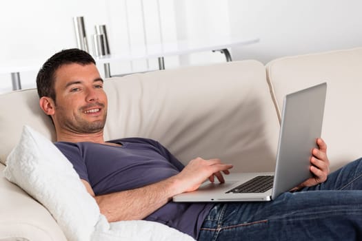 beautiful young man on sofa with computer