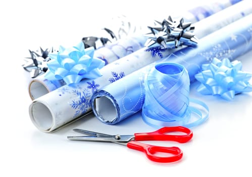 Rolls of Christmas wrapping paper with ribbons, bows and scissors