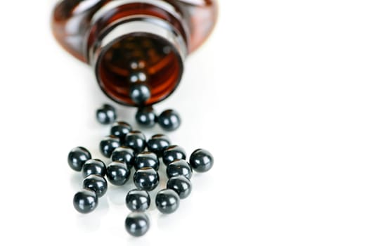 Traditional chinese herbal  medicine pills spilling from bottle on white background