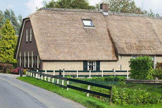 Old Dutch farm in the country with thatched roof and grocery garden
