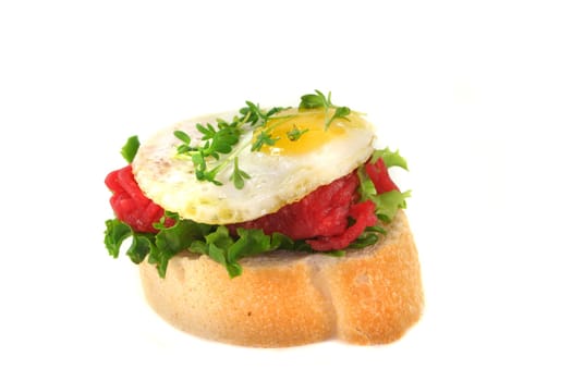 a slice of baguette with tartare and fried quail egg