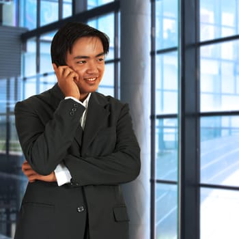 Businessman Chatting On The Phone In Front Of Windows In His Office