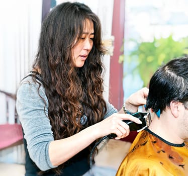 Hairdresser cutting hair in her salon with trimmer