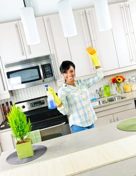 Smiling young black woman with sponge and rubber gloves cleaning kitchen