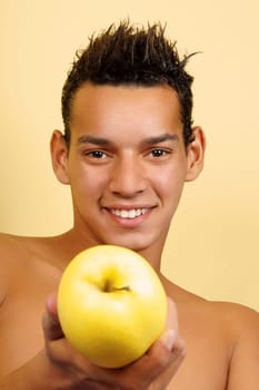 Shirtless young brazilian man offering an apple. Selective focus.