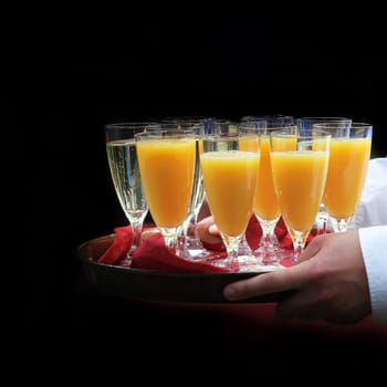 Waiter serving orange juice and sparkling wine on a tray - square