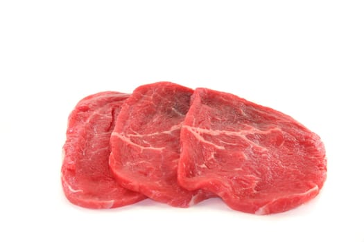 Three raw beef minute steaks against white background