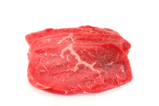 Three raw beef minute steaks against white background