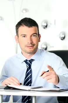 An attractive business man is writing on a paper