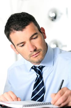 An attractive business man is writing on a paper