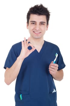 smiling male dentist holding toothbrush and showing ok sign isolated on white background