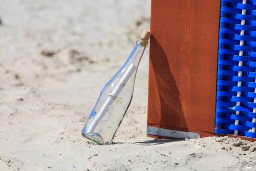 Message in a bottle leaning on a beach chair on the North Sea beach