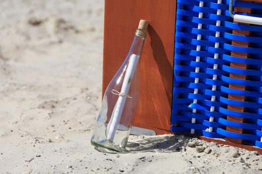 Message in a bottle leaning on a beach chair on the North Sea beach