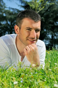 An attractive and cheerful man lying in the park