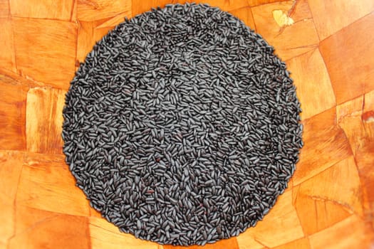 Close up of organic black purple rice in a wood bowl.