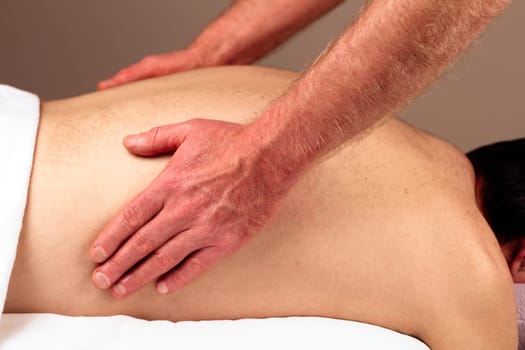 Male receiving a massage therapy from a male massage therapist.