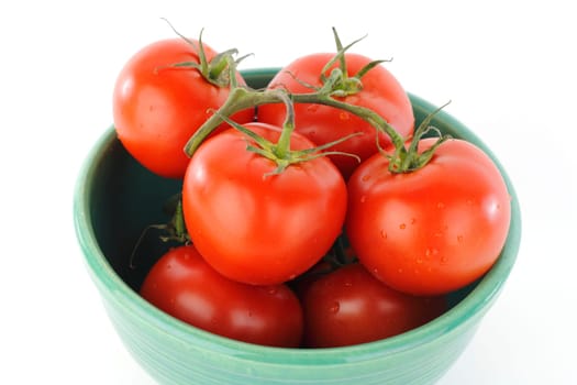 Moist red fruit with connecting green stems in a container on white background.