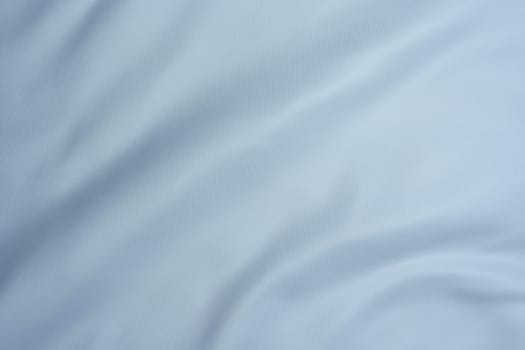 Close-up of light blue fabric with gentle folds and smooth texture, creating a minimalistic background.