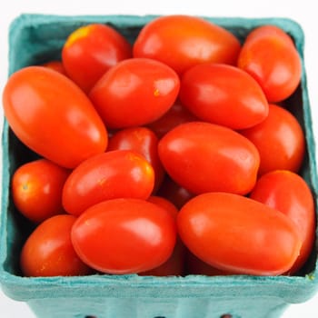 Square pint container of small red organic tomatoes.