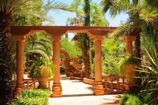 Garden trail with arches and palm trees