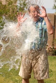 Senior man being splashed with a great deal of water