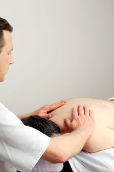Face down man receiving an upper back massage from a male massage therapist.