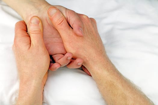 Male massage therapist hands massaging the hand of another man near the wrist.