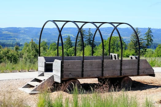 Empty benches in a step up to open stagecoach wagon made of wood and metal with logs for wheels.